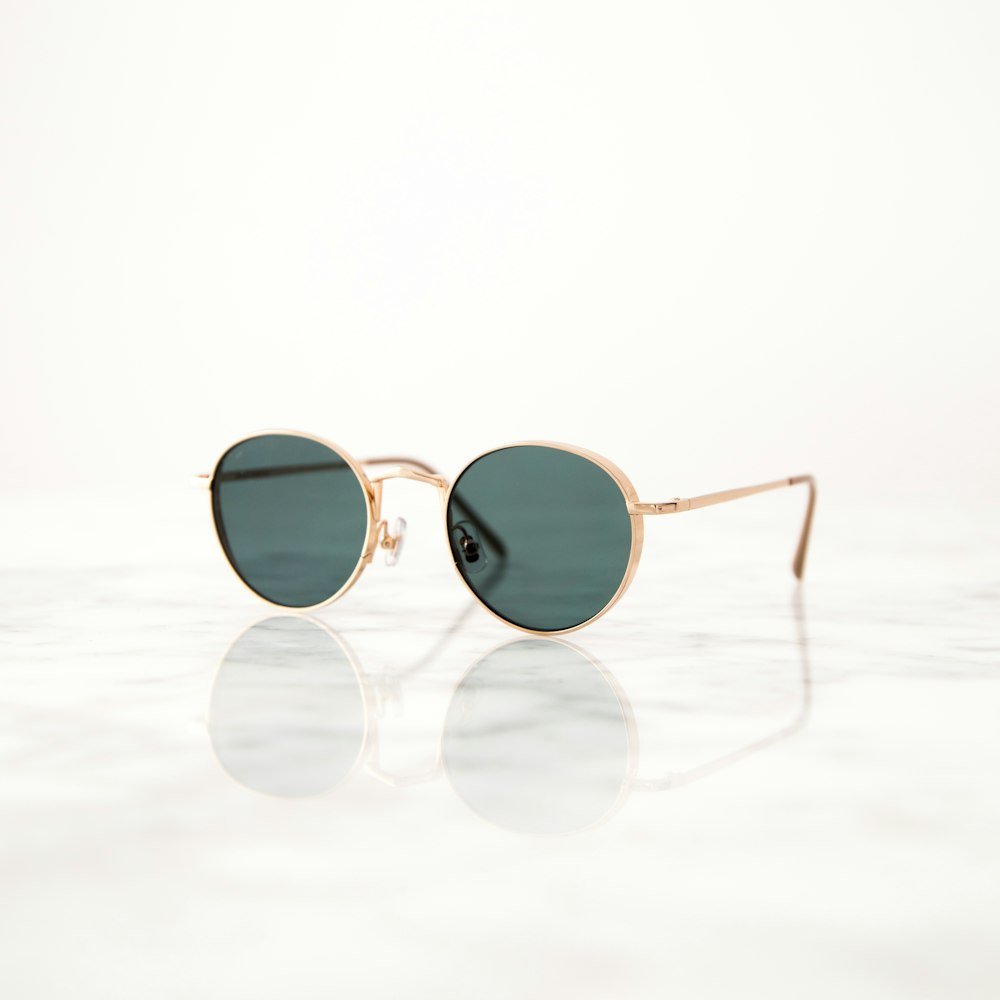 Gold-framed round sunglasses on a white surface